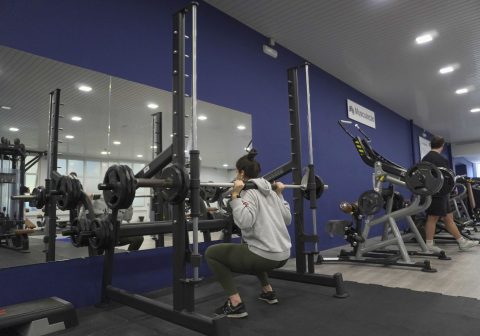 rapariga a fazer agachamentos com muito peso